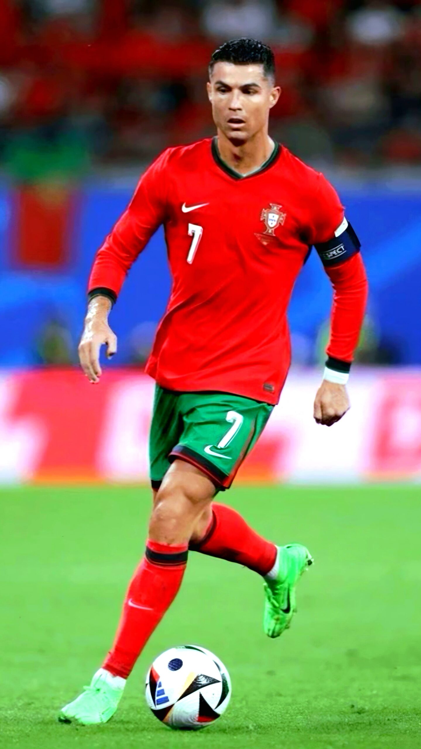A soccer player in a red Portugal jersey with number 7 and green shorts runs on the field, focused on the ball at his feet, while fans wave a Portugal flag and a blurred crowd fills the background—a moment perfect for streaming live via IPTV Suisse.