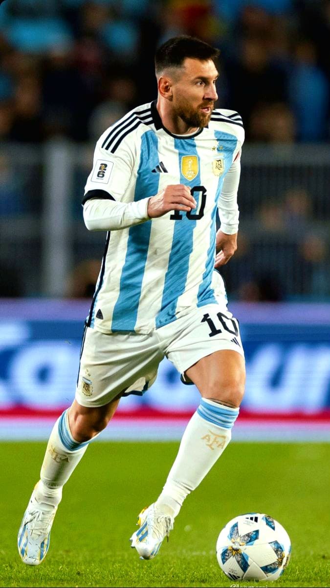 A soccer player in an Argentina jersey, number 10, runs on the field while controlling the ball during a match, as fans watch the action live via IPTV Suisse.